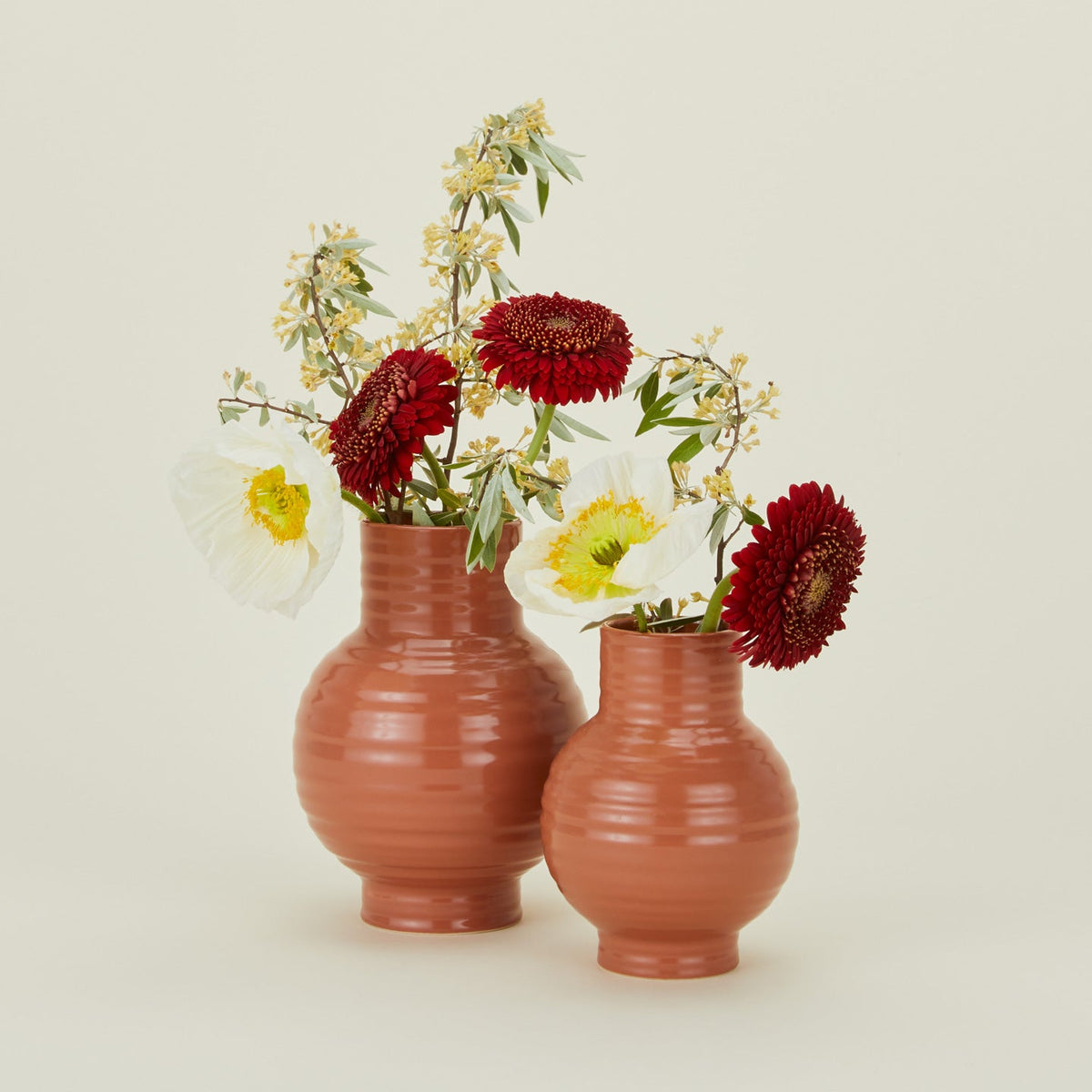 Large and small essential ceramic vases in terracotta with flowers